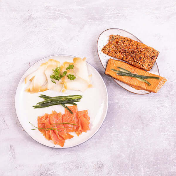 Kystfiskens røgpakke med skiveskåret hellefisk, skiveskåret laks og varmrøgede laksestykker klar til frokostbord og tapas