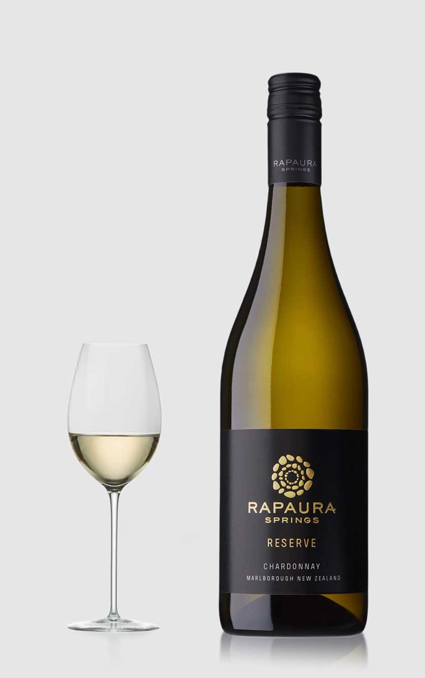 En flot flaske Rapaura Springs Reserve Chardonnay hvidvin fra New Zealands Marlborough-region serveret ved siden af et glas hvidvin på et bord