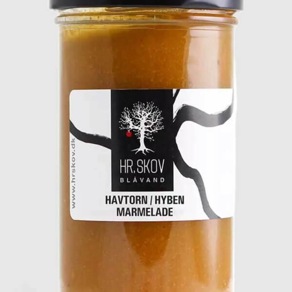 Et glas Hr.Skov havtorn og hyben marmelade med den smukke orange-røde farve serveret ved siden af luftstegte pandekager