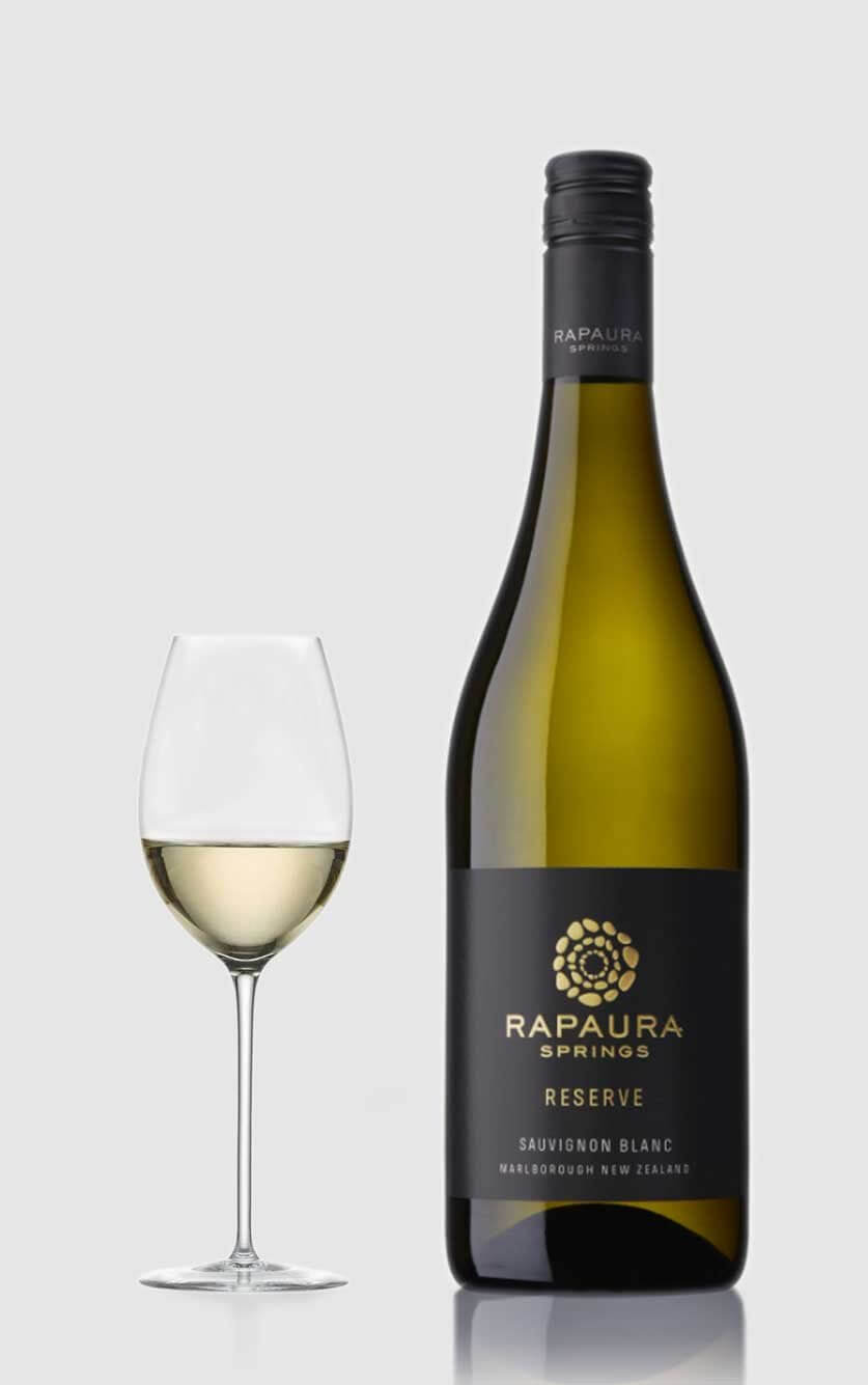 En flot flaske Rapaura Springs Reserve Sauvignon Blanc hvidvin fra New Zealands Marlborough-region serveret ved siden af et glas hvidvin på et bord