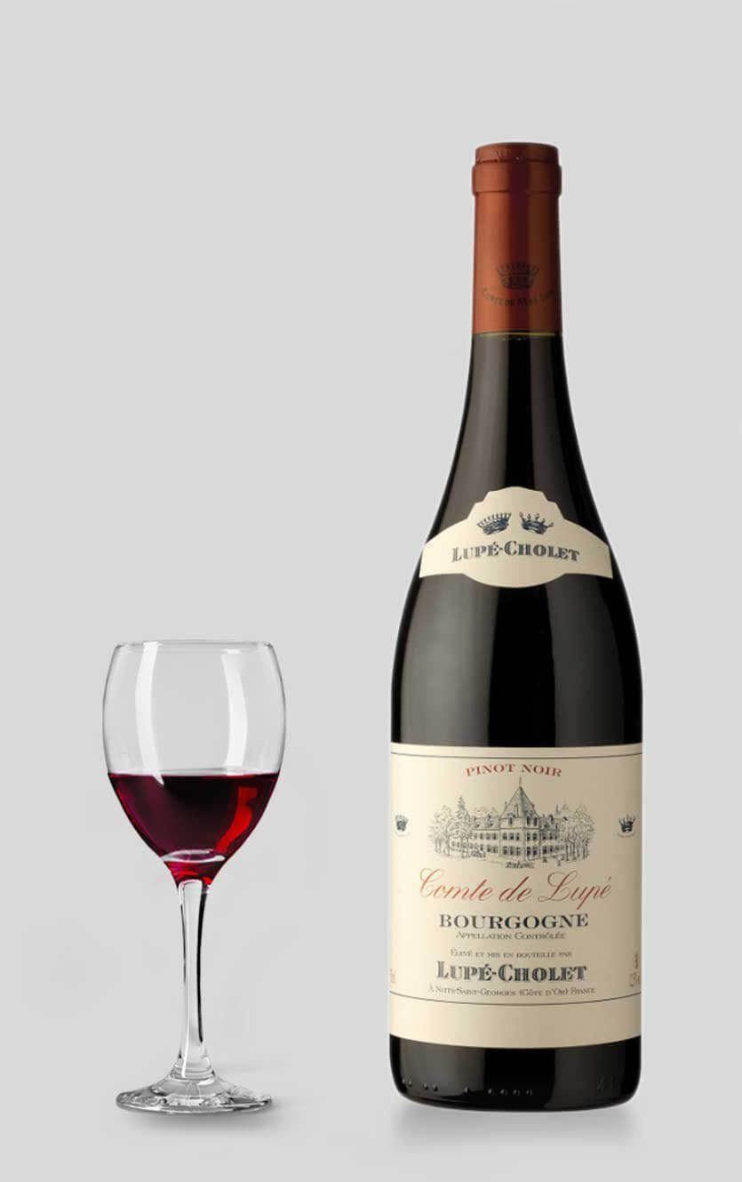 En flot flaske Lupé-Cholet Bourgogne Comte de Lupé rødvin fra Bourgogne serveret ved siden af et glas rødvin på et elegant bord