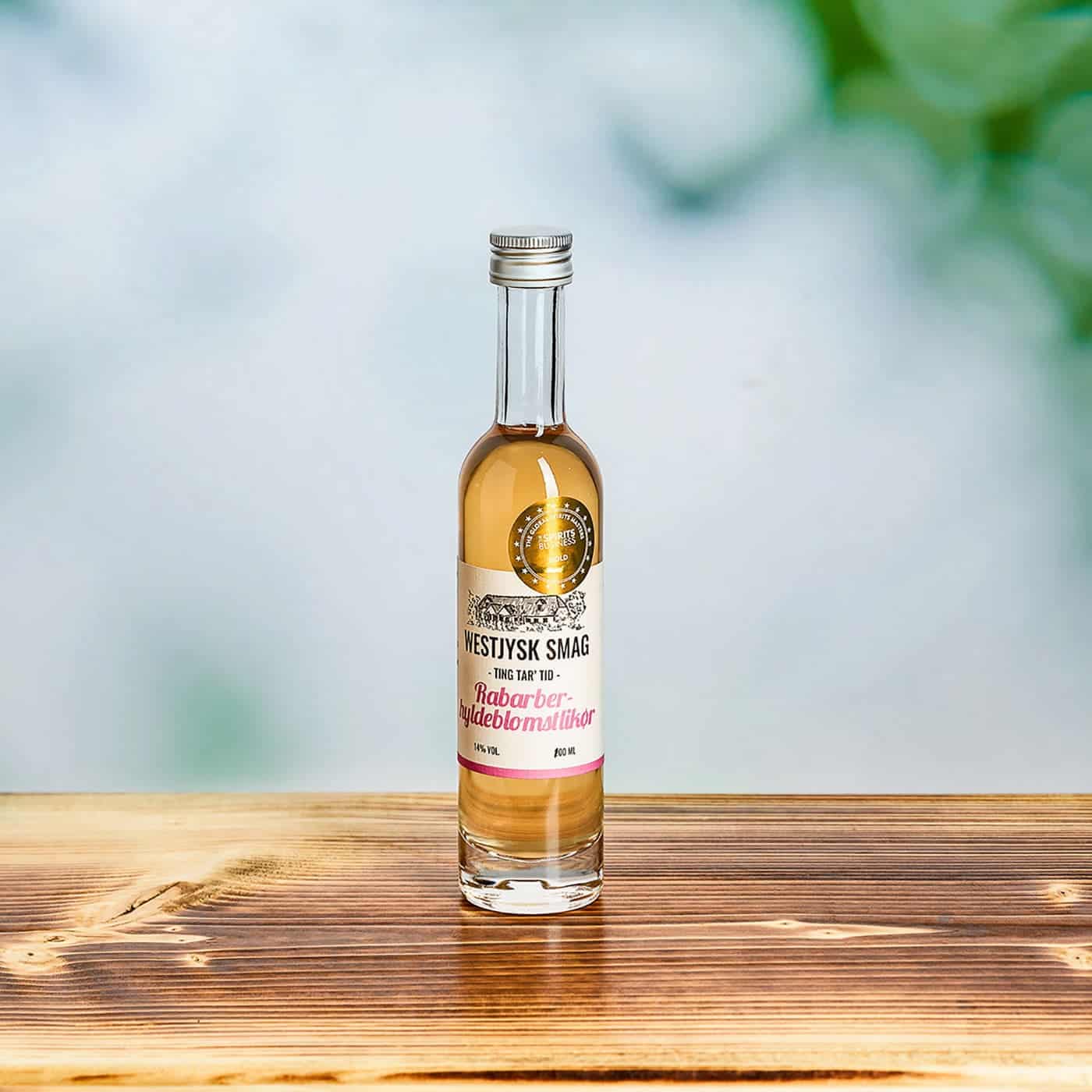Flaske med lyserød Rabarber Hyldeblomst likør fra Westjysk Smag klar til servering