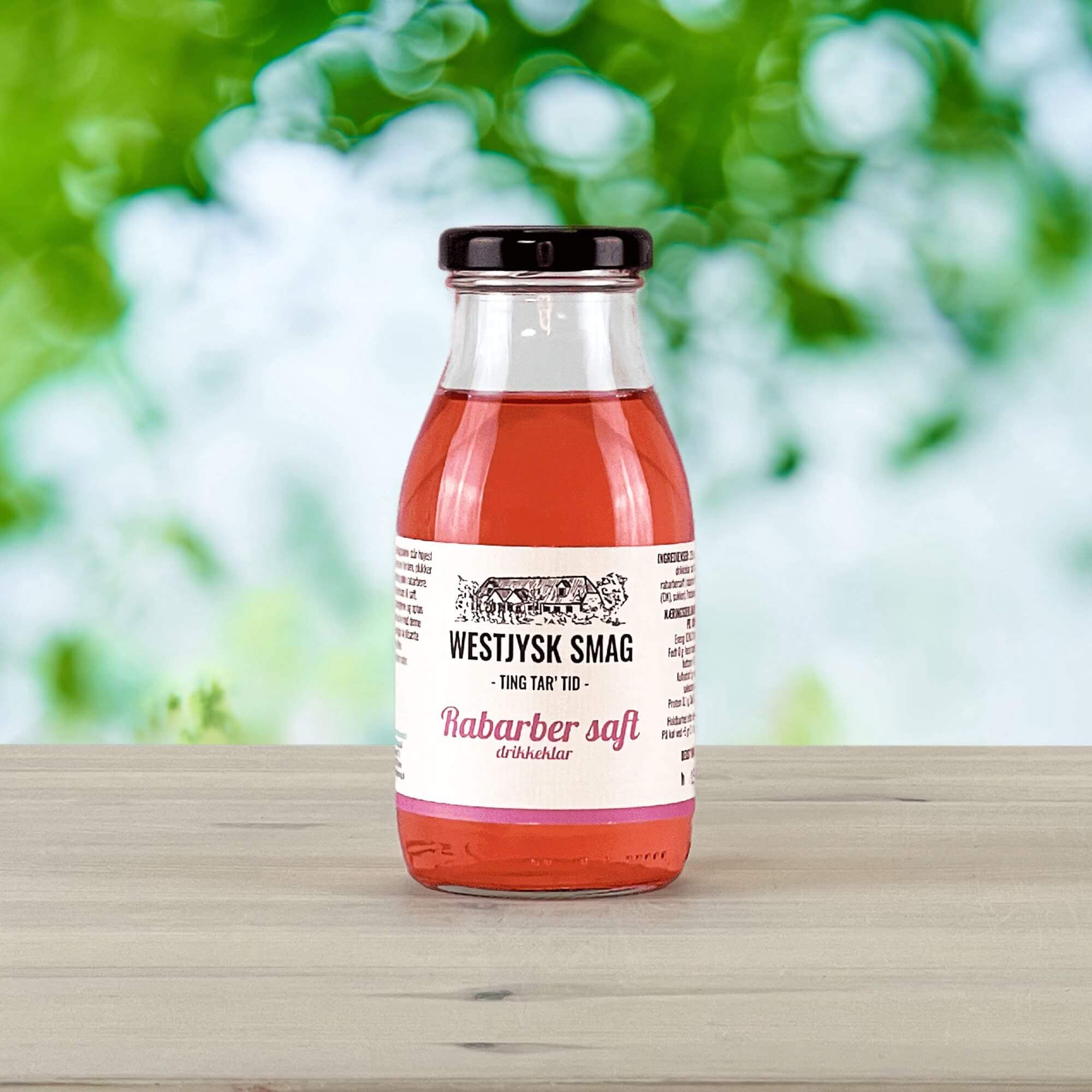 Flaske med drikkeklar rabarbersaft klar til servering som kold, syrlig sommerdrik.