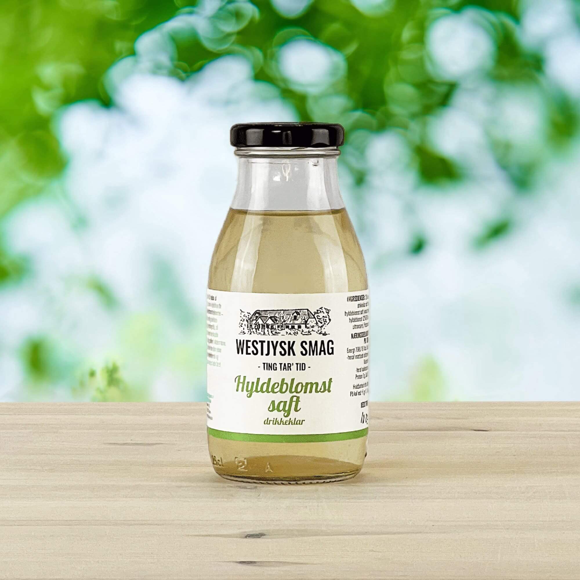 Flaske med drikkeklar hyldeblomstsaft klar til servering som kold sommerdrik.