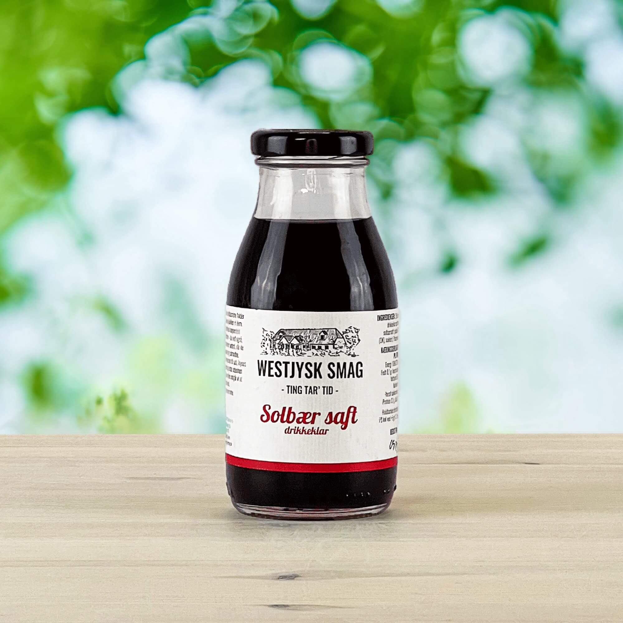 Flaske med drikkeklar solbærsaft klar til servering som kold bærdrik eller til desserter.