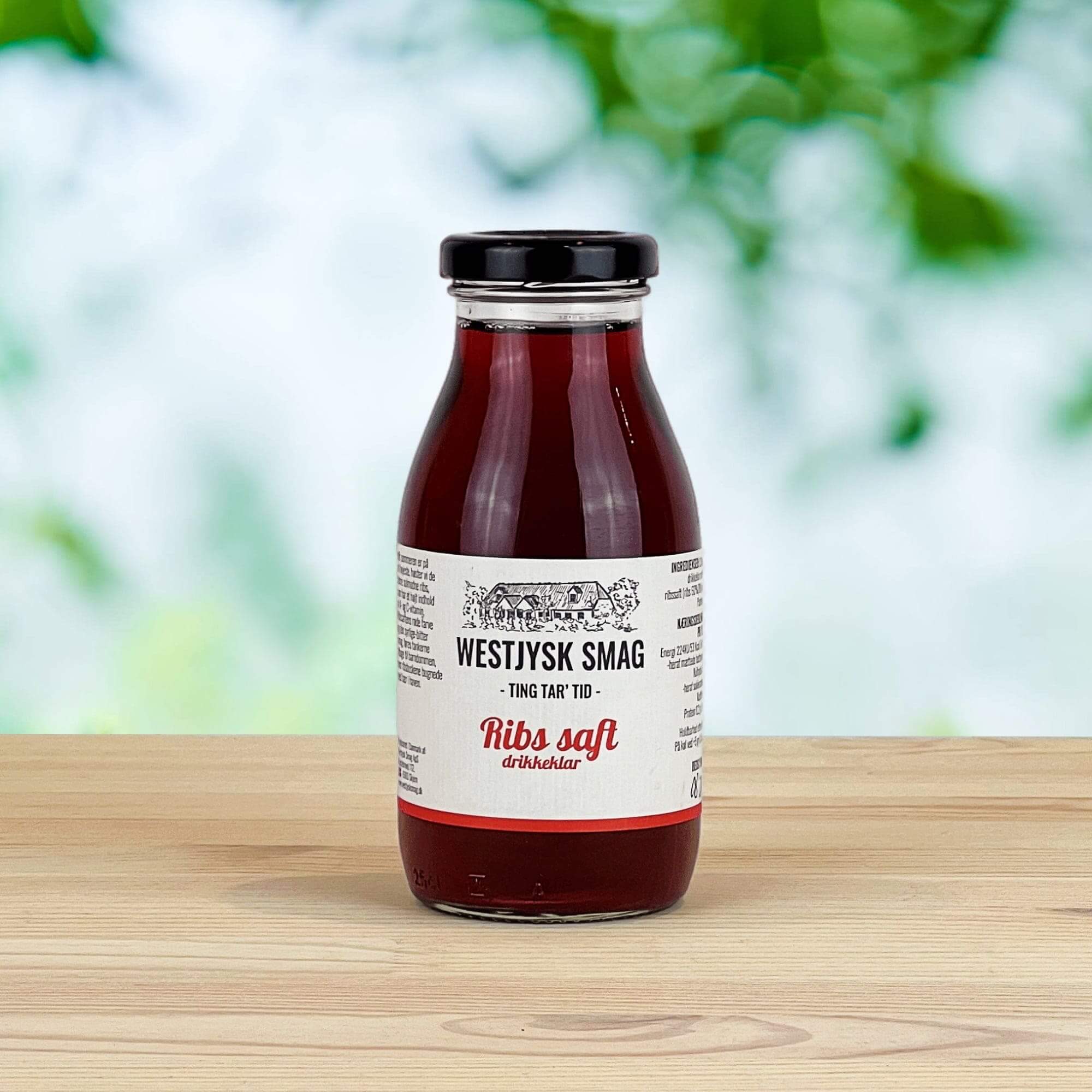 Flaske med drikkeklar ribssaft klar til servering som kold bærdrik eller til desserter.