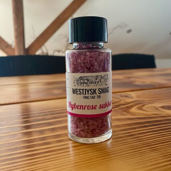 Hybenrose sukker i en glasflaske stående på et bord