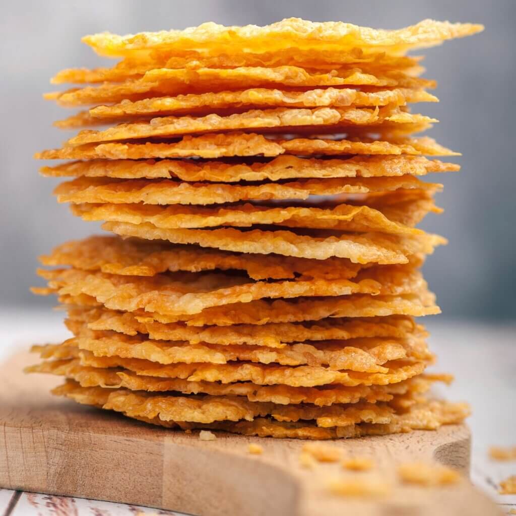 Parmesan chips stablet og flot serveret på et lyst skærebræt