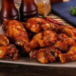 Buffalo wings z airfryera na czarnym talerzu, chrupiące w ostrym sosie
