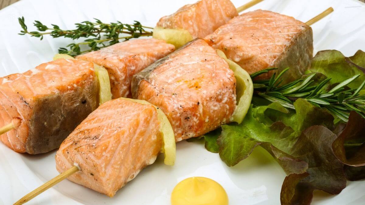 Laksespyd i min airfryer serveret på hvid tallerken med frisk salat, urter og gul dip som nem aftensmad med fisk