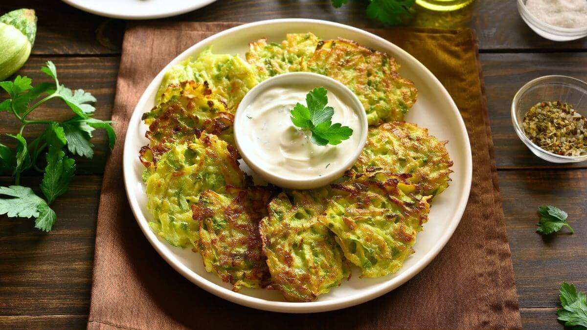 små, sprøde og saftige pandekager lavet af revet zucchini serveret på en tallerken