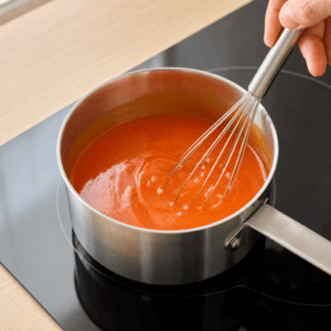 Buffalo-sauce piskes homogen og blank i en lille kasserolle