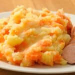 En røget pølse serveret med kartoffelmos med grøntsager. Retten er på Hollandsk, Rookworst med Stamppot