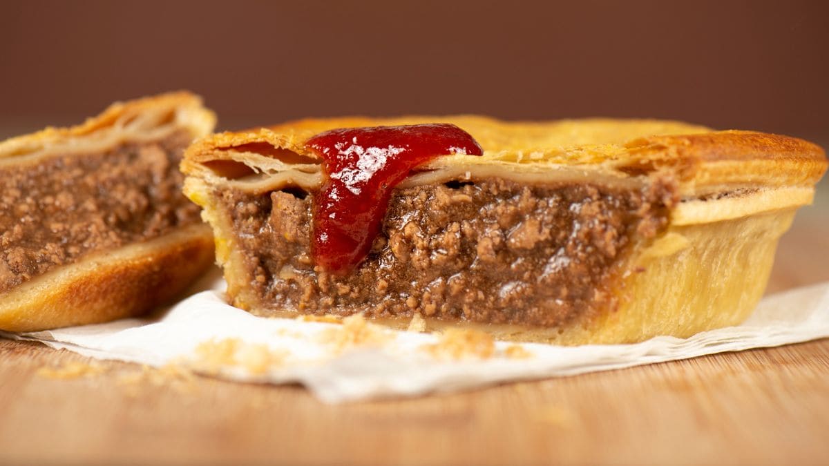 En portionsanrettet australsk tærte fyldt med hakket oksekød i en tyk, fyldig brun sovs.