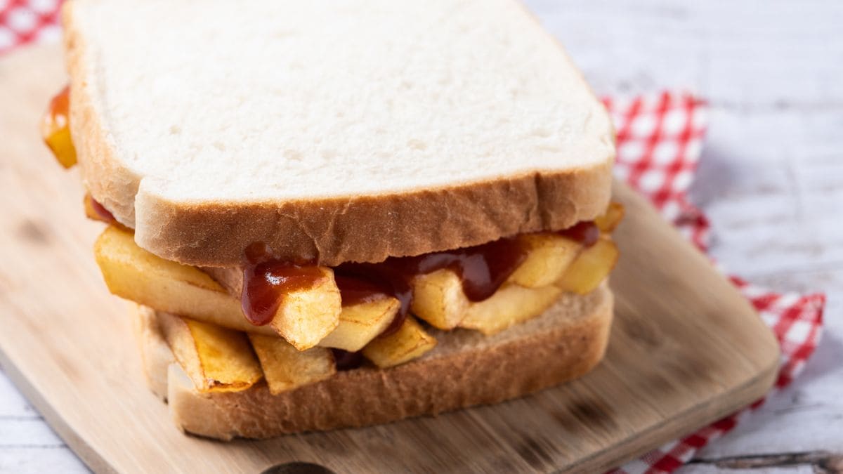 Fries som er tykke, lidt bløde indeni og drysset i salt og lidt eddike, lagt inde i et hvidt brød med smør og ketchup